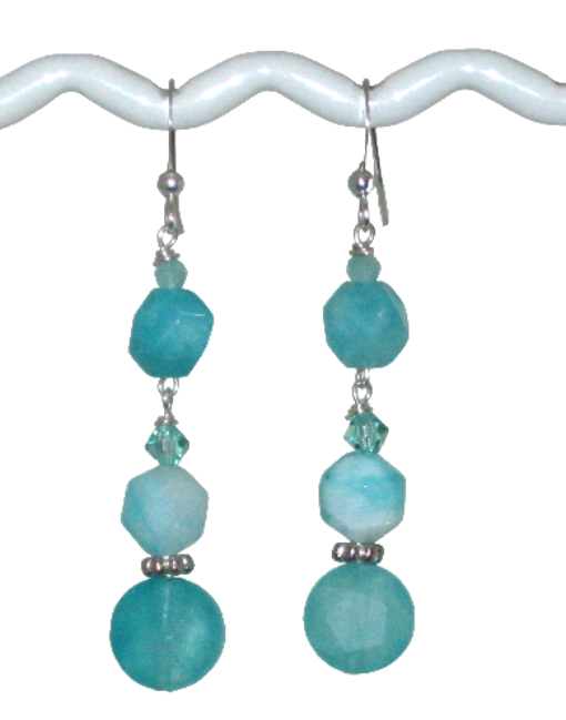 Aqua dangle earrings made with crystals and jade-style gemstone beads hanging on a white T-bar display on a white background
