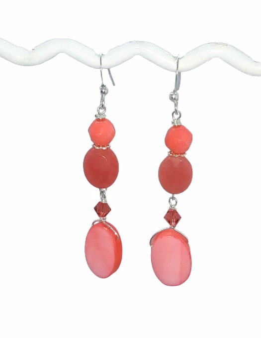 Coral-colored mother-of-pearl, coral bamboo and Jade-style gemstone beaded dangle earrings on a white background