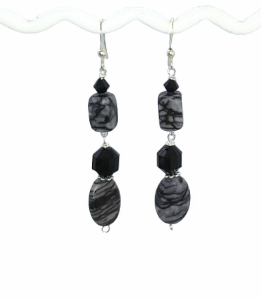 Pair of dangle earrings with black and gray Jasper gemstone beads, crystals and onyx beads hanging on a t-shaped display bar on a white background