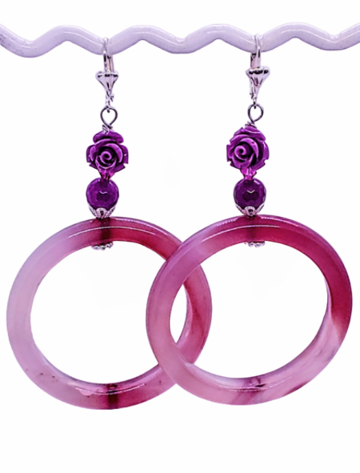 Purple and berry hued hoop beaded hoop earrings featuring a carved flowers coral bamboo gemstone bead at the top of each earring. The earrings are displayed on a white background