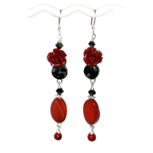 Pair of dangle earrings with red and black beads on a white background