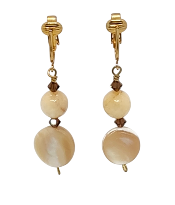 A pair of drop clip-on earrings featuring beige and cream-colored coin shell beads, round faceted jade beads and small faceted brown crystals.