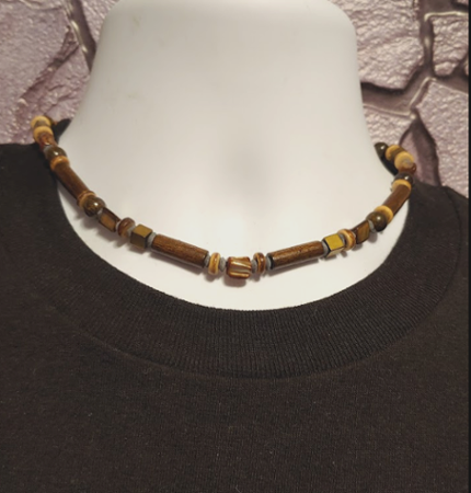 Men's beaded necklace on a mannequin with a textured background