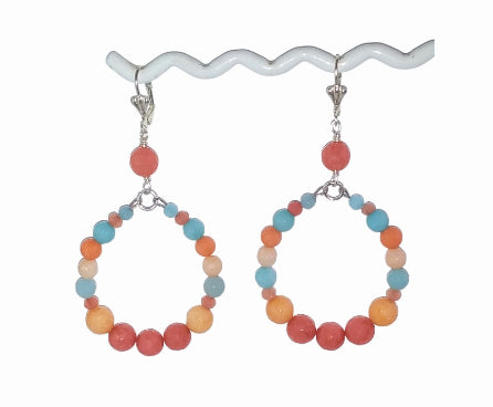 Pair of multicolored earrings with Jade beads hanging on a t-bar with a white background