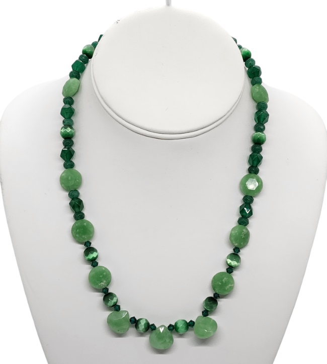 A light and dark green beaded necklace displayed on a white mannequin bust against a white background.