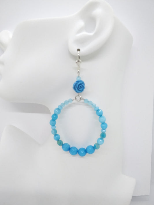Blue beaded earring on a mannequin ear with a white background