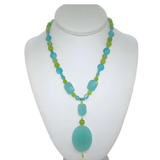 Handmade aqua and lime green beaded coastal style necklace featuring faceted cat's eye, jade beads, and a drop pendant on a white jewelry bust.