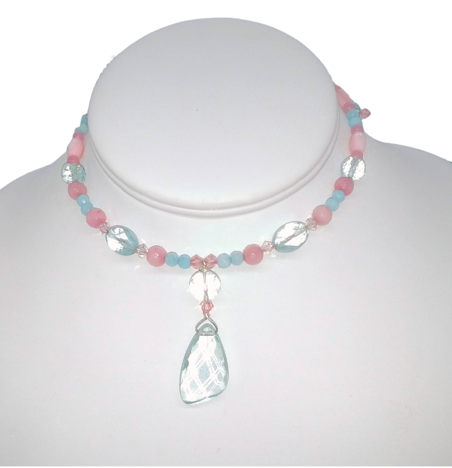 A delicate beaded blush pastel pink and aqua choker displayed on a white mannequin bust. It features pastel pink and light blue and aqua quartz beads, clear faceted round beads, and a faceted aqua quartz teardrop-shaped pendant.