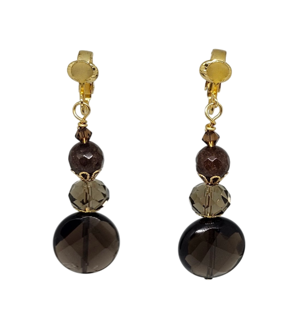 A pair of gold-tone clip-on dangle earrings featuring faceted dark brown and smoky brown beads, with large round dark brown coin-shaped beads at the bottom.