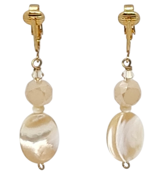 A pair of gold-tone clip-on dangle earrings featuring faceted round beads and larger oval mother-of-pearl beads, shown against a plain white background.