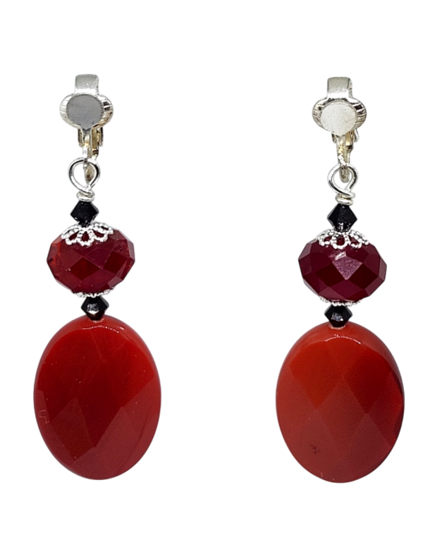 A pair of drop earrings featuring large, faceted red oval stones suspended from smaller red faceted beads and black crystal beads, with silver-toned ear clips.