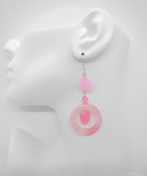 Pink circular earring on a mannequin ear with a white background