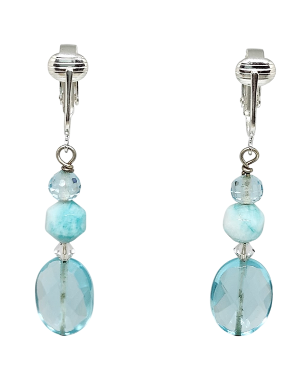 A pair of clip-on dangle earrings featuring faceted light aqua green beads of varying shapes, including a large oval.  Each earring also has a clear bicone crystal.
