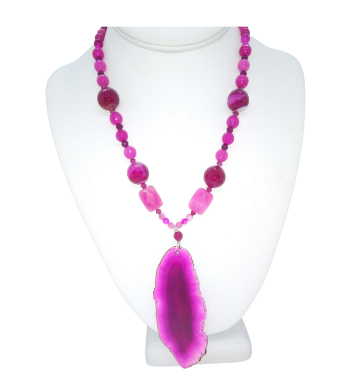 A vibrant fuchsia magenta and pink beaded necklace with a large polished agate geode pendant, displayed on a white mannequin bust against a white background.