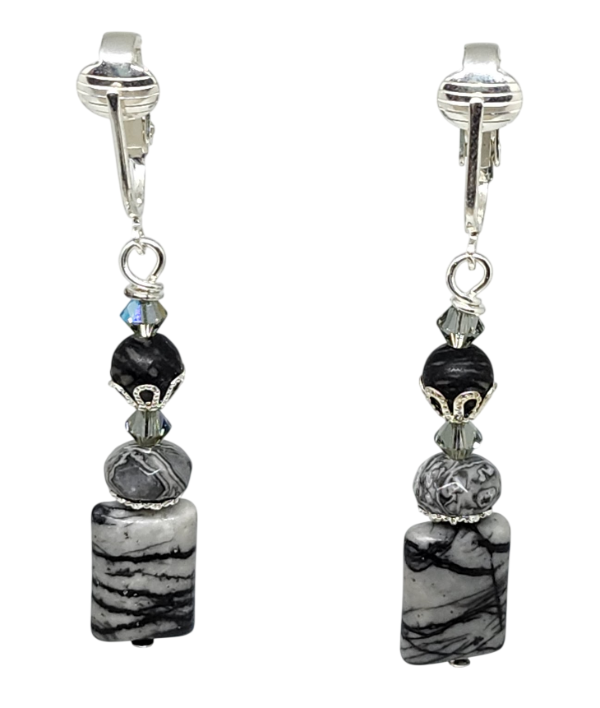 A pair of drop clip-on earrings featuring black and gray marbled  semi-precious beads, a dark round stone, and a small faceted crystal.