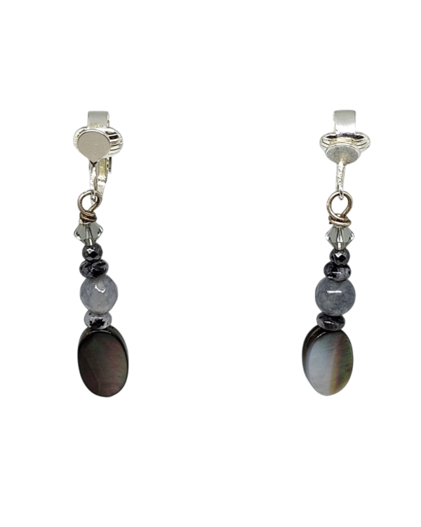 A pair of clip-on earrings featuring a large oval dark gray shell bead, smaller dark gray beads, and clear faceted crystal accents.