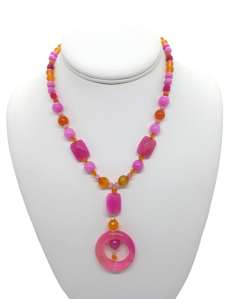 Colorful beaded necklace with a pink pendant on a mannequin bust.