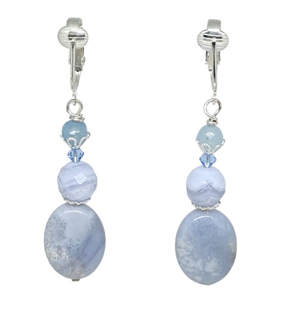 A pair of light blue clip-on dangle earrings featuring agate, jade, and crystal beads, shown against a plain white background.