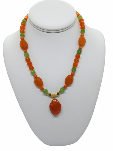 Necklace with orange and green beads on a white mannequin bust