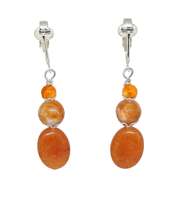 A pair of drop earrings featuring three stacked orange stone beads in oval and round shapes, suspended from silver-toned ear clips.