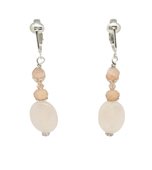 A pair of light peach drop clip-on earrings featuring faceted oval jade stones, faceted glass, and bicone crystals shown against a plain white background.