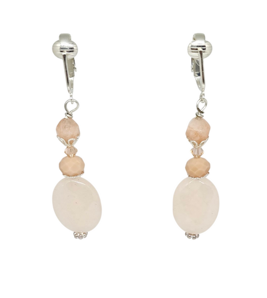 A pair of light peach drop clip-on earrings featuring faceted oval jade stones, faceted glass, and bicone crystals shown against a plain white background.