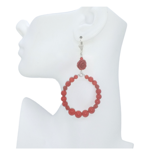 A single drop earring displayed on a white mannequin head profile. The earring features a silver-tone hook and connector with a carved coral-red rose gemstone beads leading to a large circular drop made of coral-red round beads and dyed Jade beads