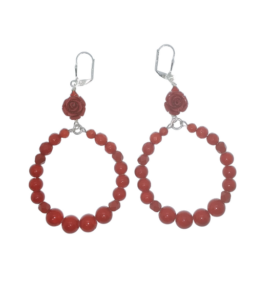 A pair of red beaded hoop earrings with a flower accent and crystal at the top of each earring. The earrings contain faceted and smooth coral bamboo beads and jade-style gemstone beads. They hang on silver leverbacks