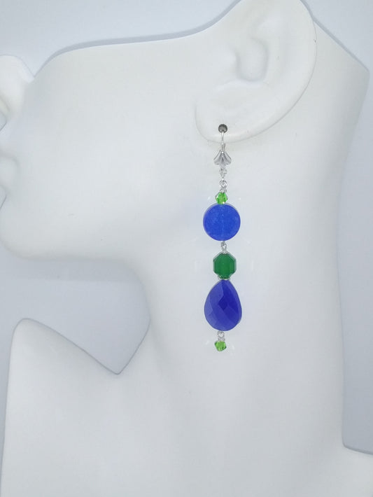Royal blue and emerald green dangle earring with crystal accent hanging on a mannequin ear.