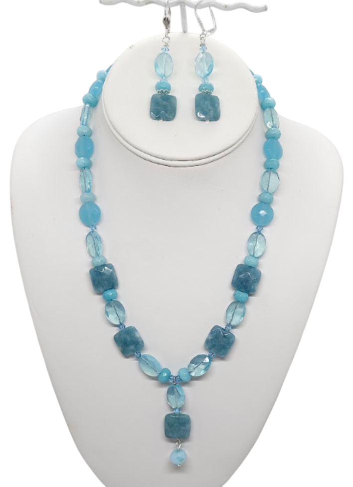 A blue beaded gemstone and crystal jewelry set featuring a necklace and matching drop earrings displayed on a white mannequin bust against a white background.