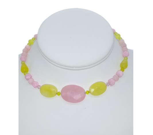 A pink and bright yellow beaded choker displayed on a white mannequin bust, featuring a large central pink oval beads flanked by two larger yellow oval beads 